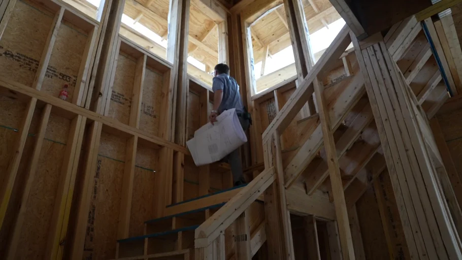 Justin Cabral walking through residential framing with construction drawings